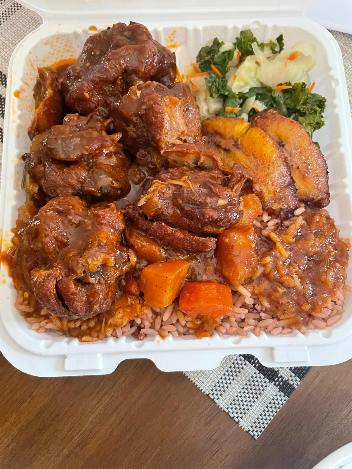 Brown stew chicken in a rich gravy with rice and peas