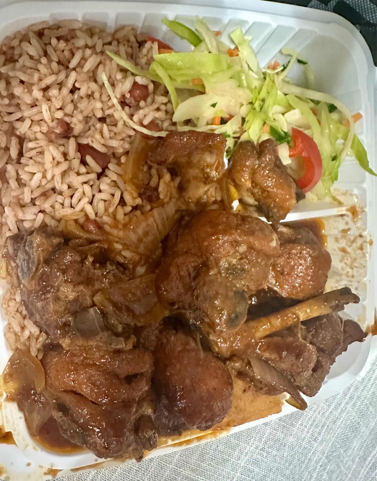 Brown stew chicken with dumplings, rice and peas and salad