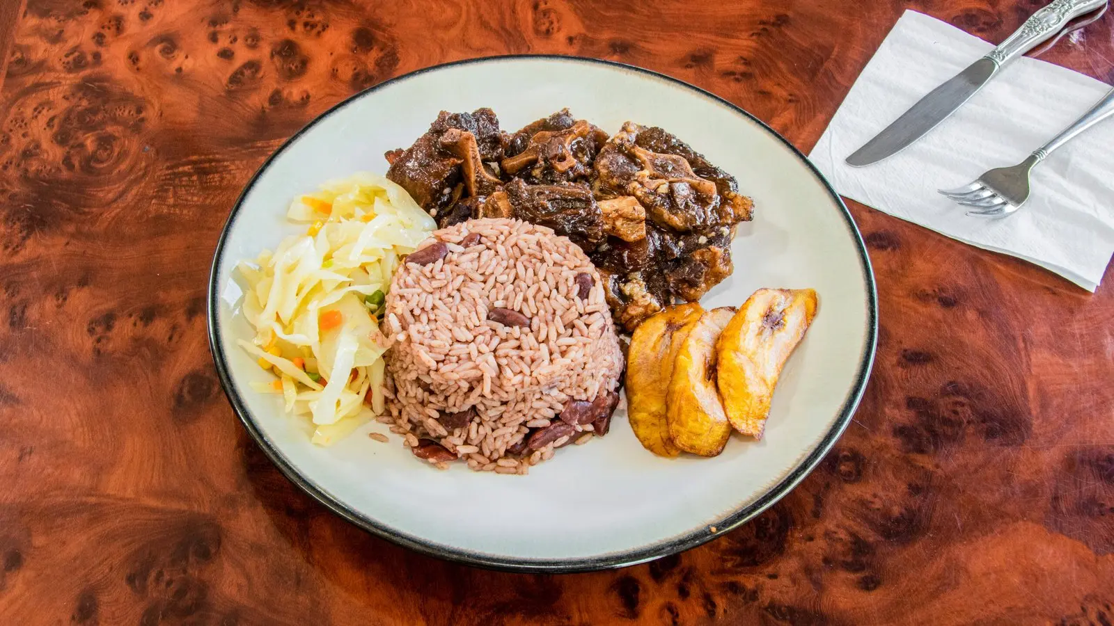 Oxtail braised in gravy with carrots and butter beans, served over rice